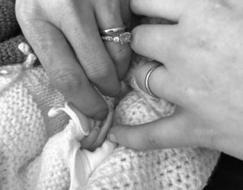 Naomi and her wife’s hands with baby Remi who was a stillbirth at 24 weeks.