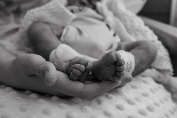A mum holding her daughter’s feet after her stillbirth.