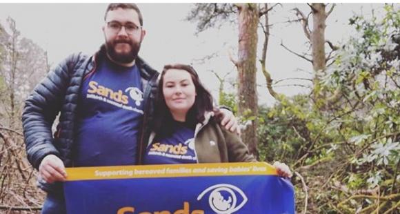 Jazz and Adam holding Sands banner