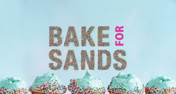 Bake for Sands words made out of sprinkles with row of blue iced cupcakes below