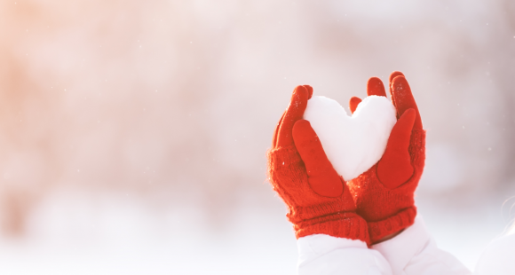 Red gloves holding snow heart