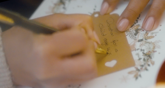 a hand writing on a Christmas present label