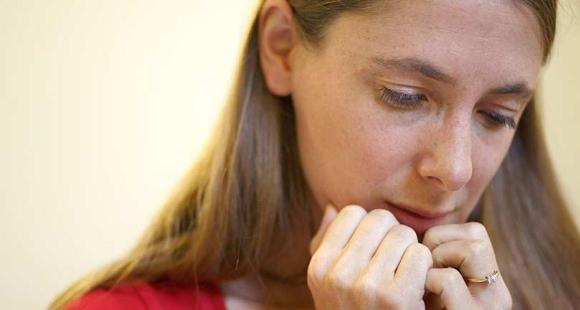 woman looking sad, holding her hands up to her chin