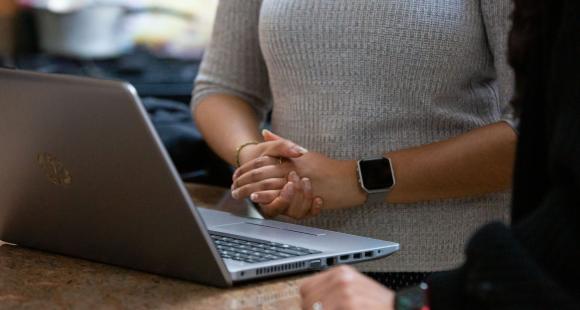 Image of people stood in front of a laptop