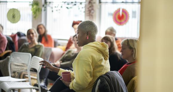 A lady sat and talking to a group of people in a support setting