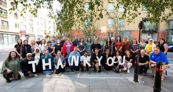 A group of people gathered together holding up letters that spell out thank you
