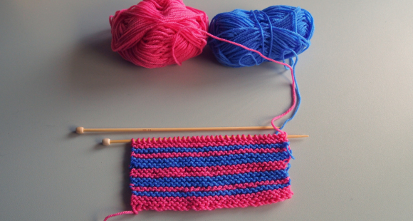 pink and blue yarn being knitted together