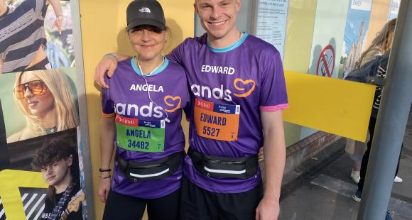 Two runners standing close to each other smiling, and wearing purple t-shirts