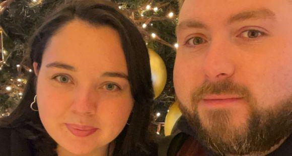 A lady with dark hair and a man with a beard looking at the camera with twinkling tree lights in the background after talking about neonatal care of their daughter.