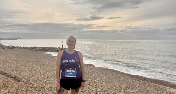 A woman standing up on pebble beach and sea