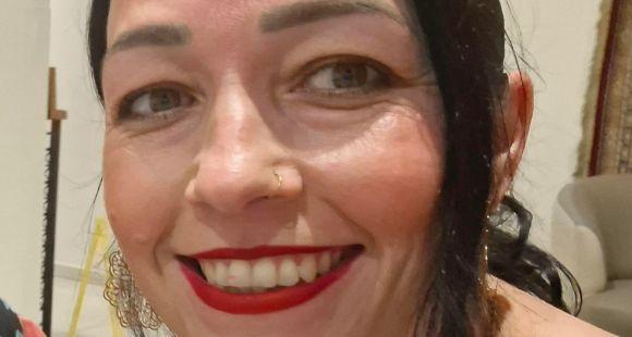 A lady with dark hair wearing red lipstick smiles at the camera after talking about Group B Strep.