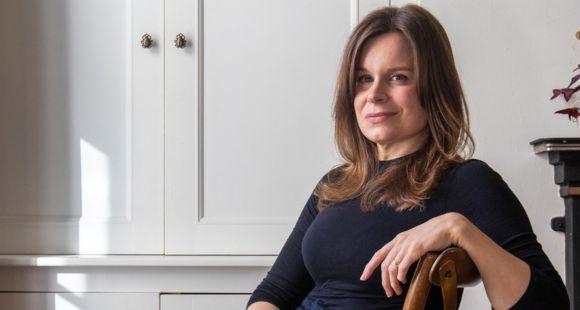A lady with dark hair sits in a chair and looks at the camera after speaking about the stillbirth of her daughter Wren.