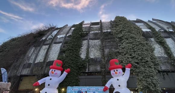 Building with greenery on it, Two snowman and a crowd of people.