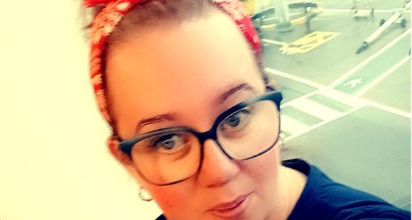 Lady with red hair and black glasses looking at the camera