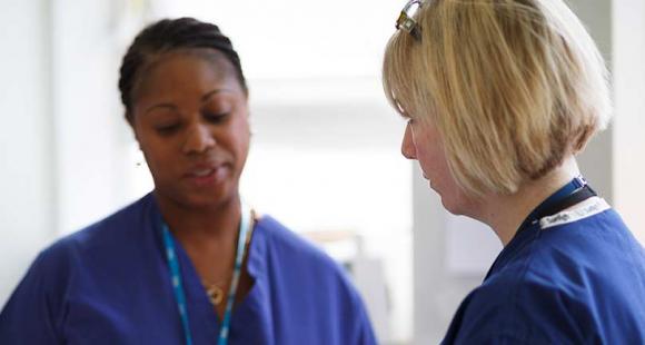 A black female nurse and a white female nurse in conversation