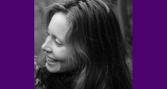 A lady in a grey picture looking sideways and smiling after talking about her TFMR.