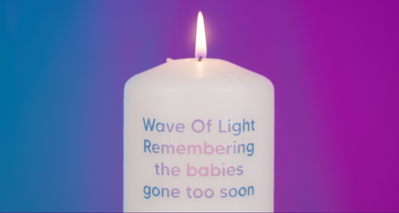 A lit candle with the words Wave of Light remebering the babies gone too soon