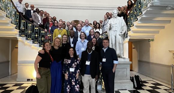 A large group of people span a double staircase whilst posing for a photograph 