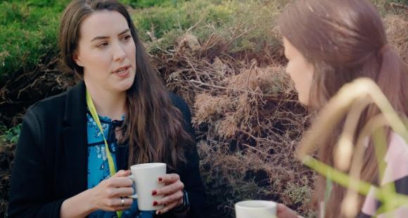 Two women sitting outside talking and having a cup of tea