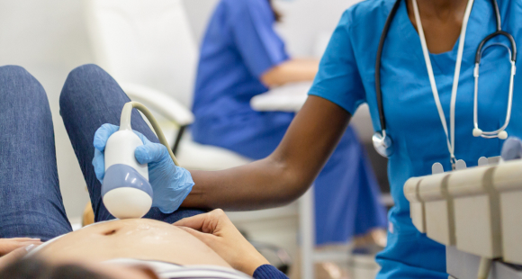 A midwife is scanning a pregnant patient who is in her late 1st or early 2nd trimester