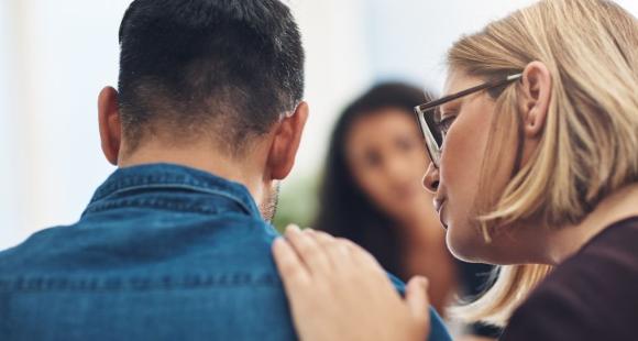 Woman with comforting hand on mans shoulder