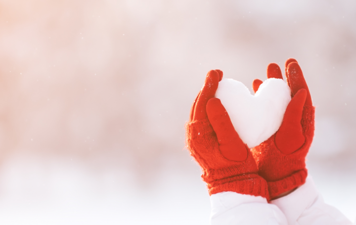 Red gloves holding snow heart