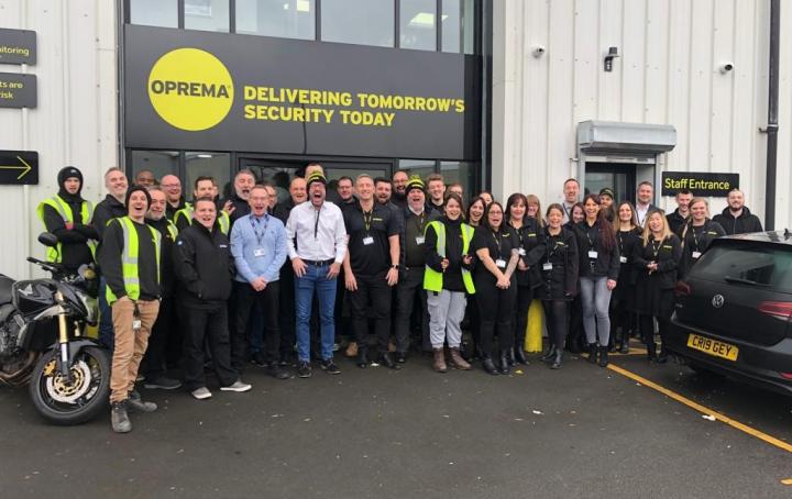 Around 30 Oprema staff members stood outside their office building smiling at the camera.