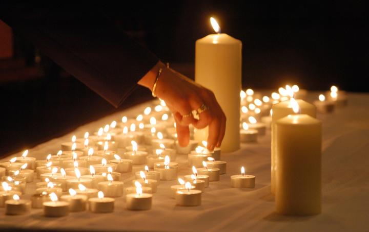 a photo of many tea candles with a female hand reaching to pick one of them up