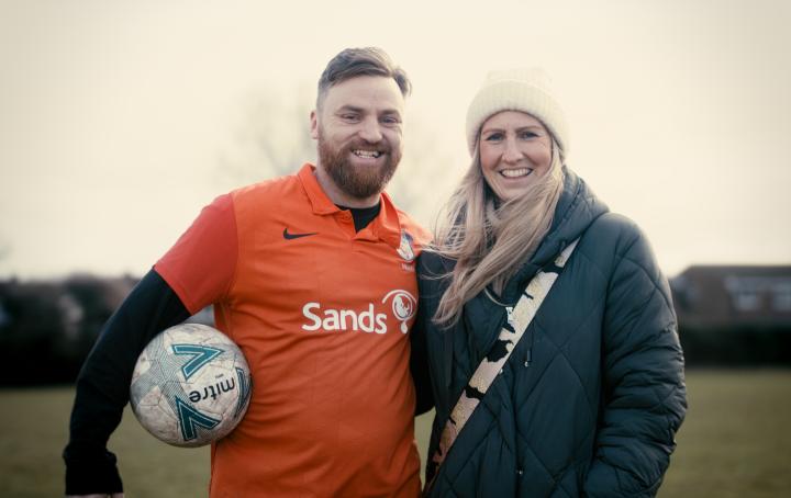 Rob Allen wears a Sands United kit and stands next to his wife Charlotte