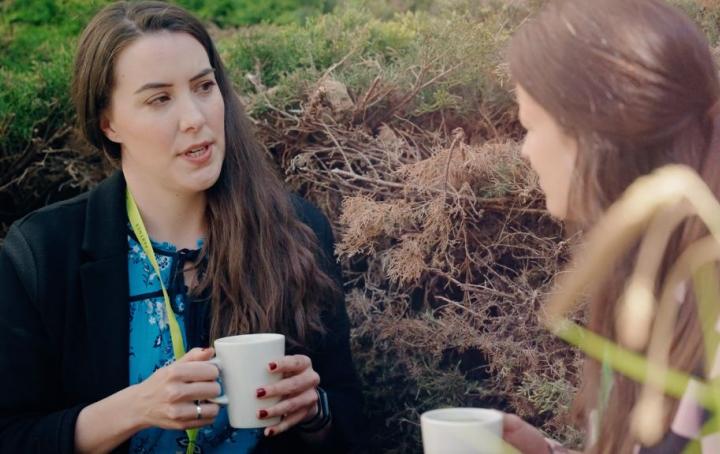 Two colleagues sat talking on a bench outside