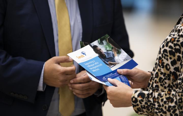 A colleague stood with their line manager who is holding a Support for your colleagues leaflet