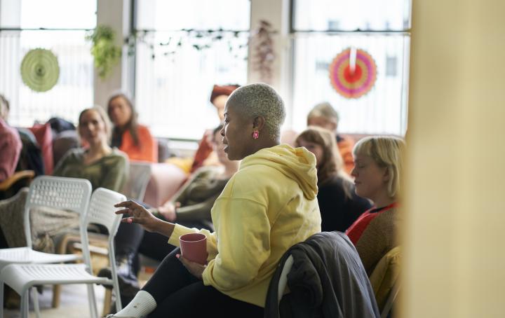 A lady sat and talking to a group of people in a support setting