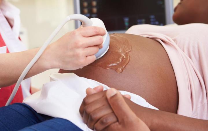 A pregnant lady lying down on a hospital bed and having an ultrasound