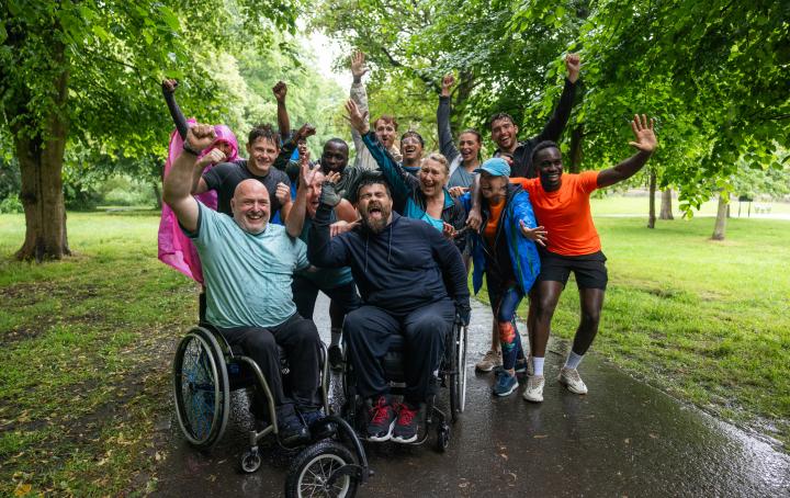A group of people together and cheering after completing a fundraising activity in a park
