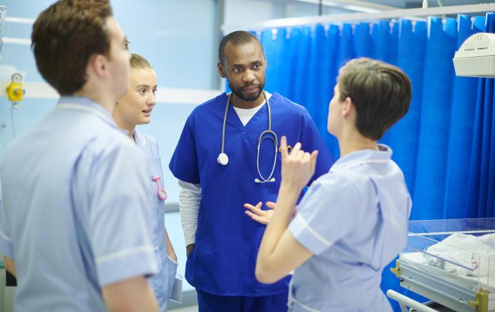 A group of healthcare professionals stand together talking. They