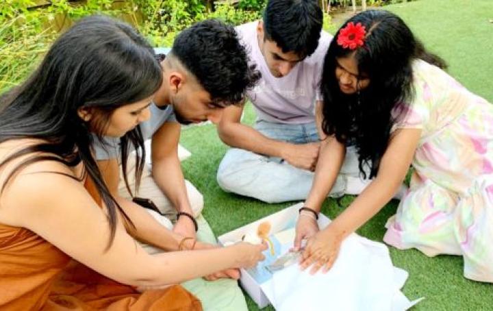 A group of siblings sat together on the floor looking through a Sands Muslim Care Box