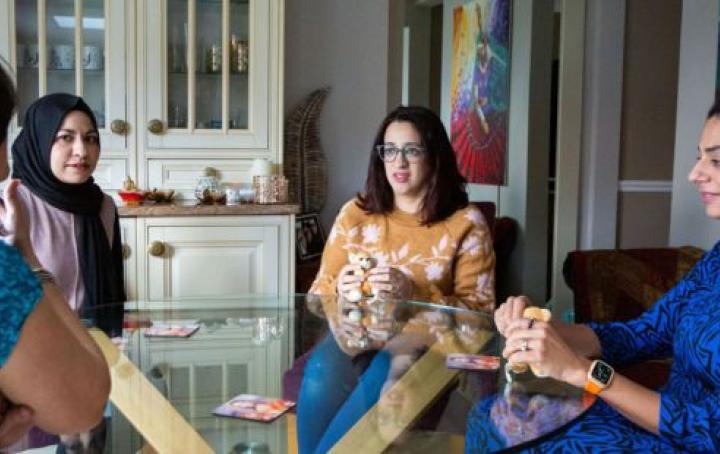 A group of bereaved South Asian mothers sat around a table talking