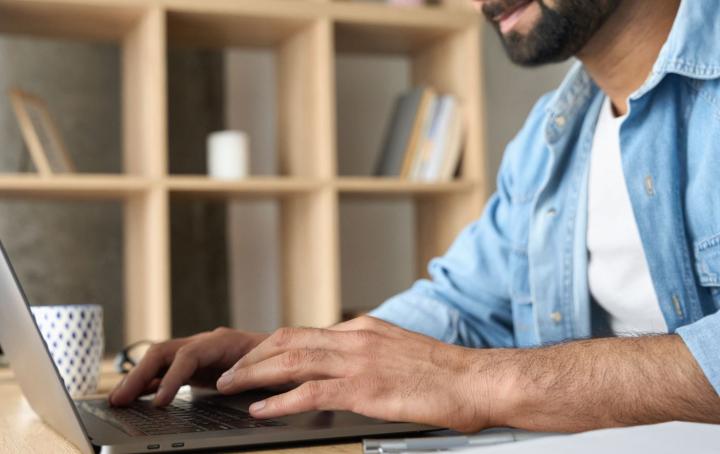 A man sat at a table using a laptop