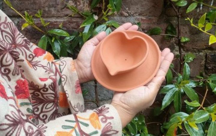 lady holding a heart-shaped diya
