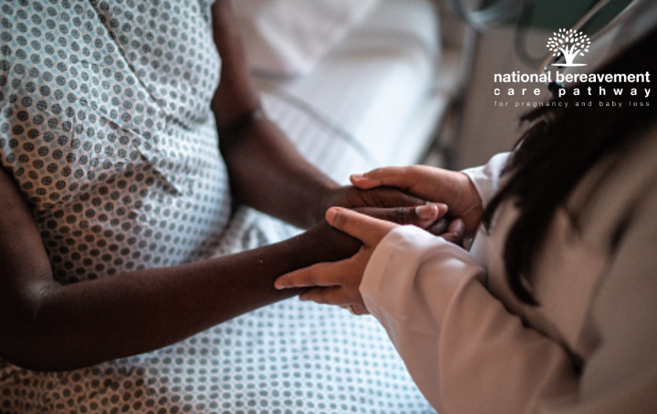 A health professional holds the hands of a black female patient