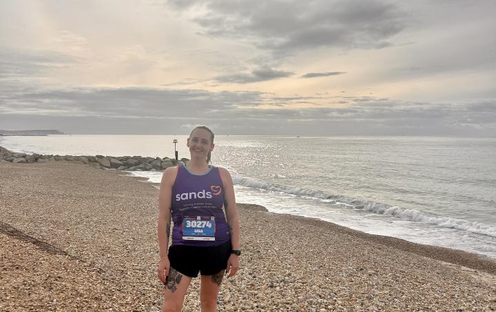 A woman standing up on pebble beach and sea