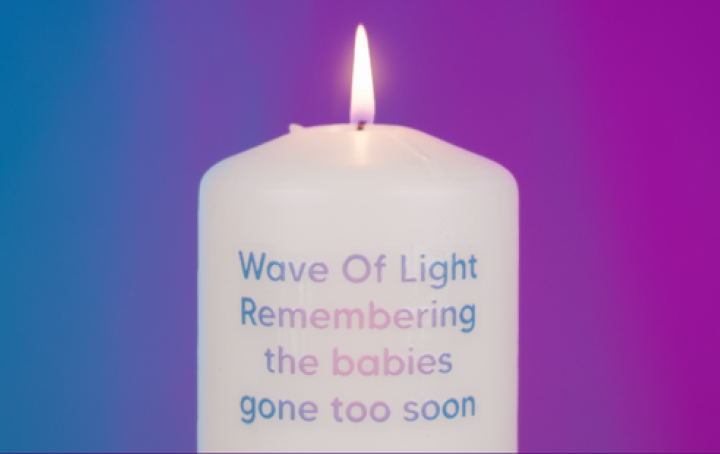 A lit candle with the words Wave of Light remebering the babies gone too soon