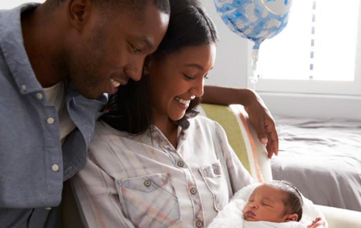 Black mum and dad smile at their baby