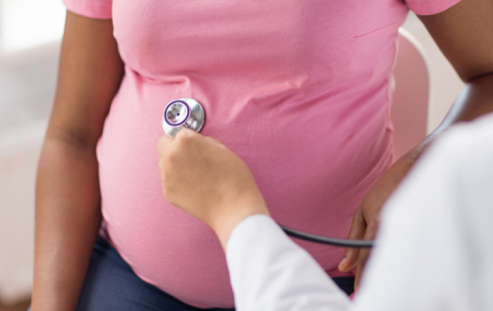 Pregnant woman in pink top is examined by doctor