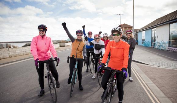 Group of smiling cyclists fundraising for Sands on a seaside ride